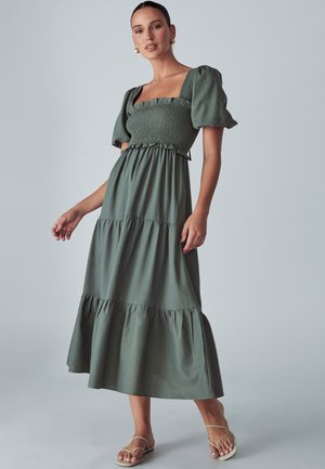 Roheline maksikleit ruudukujulise kaelusega, puffvarrukatega, smockitud rinnaosaga ja kihilise alläärmega. Valmistatud kergest kangast, millel on pehme tekstuur.