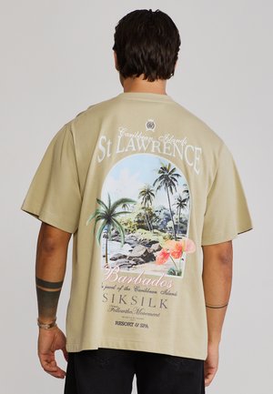 Muž v béžovom tričku s farebnou tropickou grafikou St Lawrence Barbados, palmami, kvetmi a textom na chrbte.