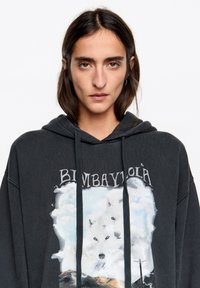 Oversize'owa czarna bluza z kapturem z nadrukiem dwóch białych wilków otoczonych chmurami. Posiada kaptur z sznurkiem oraz miękką teksturę.