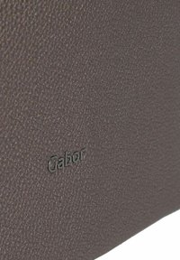 Bruin gestructureerd leer met een subtiele nerf, voorzien van een geperst "Gabor" logo. Het ontwerp is slank en minimalistisch.