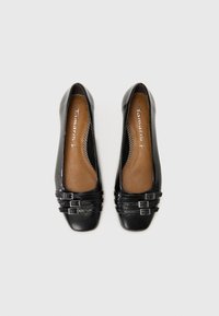 Ballerines noires avec un dessus en cuir lisse et une texture subtile, bout carré, et trois boucles décoratives sur la lanière avant.