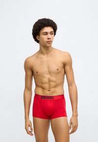 Piros boxer alsó fekete derékpánttal, amelyen a "DIESEL" embléma látható. Sima pamut anyag, testhez simuló szabás, és combközépig érő hossz.
