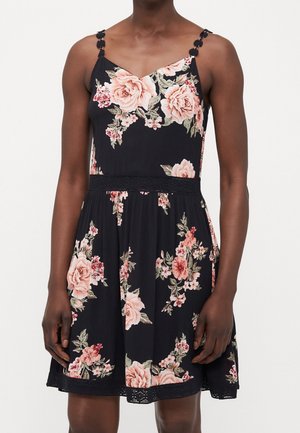 Ärmelloses schwarzes Kleid mit pinkem und pfirsichfarbenem Blumenmuster, tailliertem Schnitt und Spaghettiträgern mit dekorativen Blumenakzenten.