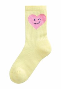 Rumena rebrasta nogavica z rožnato srce z nasmejanim obrazom. Mehka tekstura, dolžina do sredine meč, zaobljen prst.