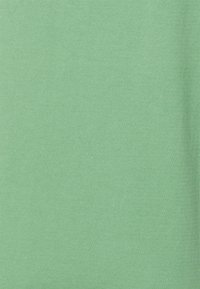 Tissu uni texturé d'une couleur verte douce, montrant un motif de maille fine et une surface lisse.