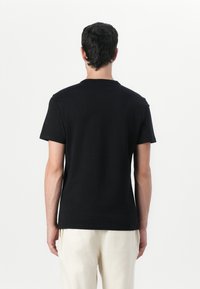 Black cotton t-shirt with short sleeves and a crew neck, featuring a smooth texture and a simple, minimalistic design.