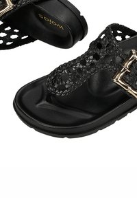 Sandal nero con design a strisce intrecciate e una fibbia d'accento dorata lucida. Presenta una suola interna testurizzata e una suola piatta in gomma imbottita.