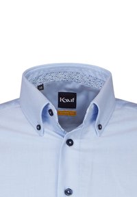 Camicia azzurro chiaro con taglio moderno. Presenta bottoni neri e una fodera interna del colletto a motivo floreale. Il materiale sembra liscio e tessuto.