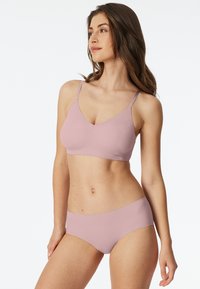Light pink wireless bra and matching brief set. Soft, smooth fabric with a seamless design and adjustable straps. Minimalist style.