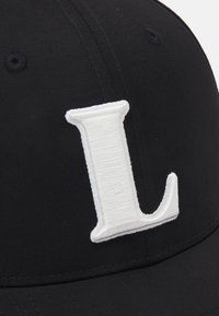 Casquette noire avec un "L" blanc brodé en relief à l'avant. Tissu lisse avec des coutures visibles et un design structuré.