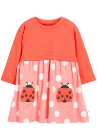 Robe longue corail à manches longues avec une jupe à pois, ornée de deux coccinelles brodées sur les poches. Tissu doux, coupe décontractée.