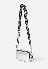 Borsa a tracolla metallica argento con forma rettangolare, caratterizzata da una chiusura con zip e una tracolla brandizzata in bianco e nero. Superficie liscia, design minimale.
