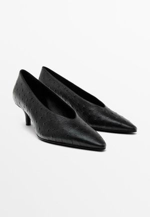 Paar schwarze, spitz zulaufende Damenhalbschuhe mit niedrigem Absatz und einem strukturierten Punktemuster auf glattem Leder.