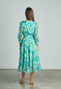 Abito midi a strati con motivo acquerello blu e verde, dotato di maniche lunghe, vita cinched e un tessuto morbido e fluido.