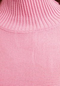 Roze gebreide trui met een hoge ribbelkraag, met een soepele textuur en een gelijkmatige steekpatroon over de stof.