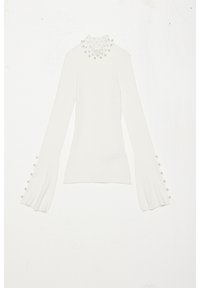 Biały prążkowany top z długim rękawem i wysokim kołnierzem ozdobionym perłami, z rozkloszowanymi rękawami i guzikami przy mankietach.