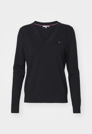 Schwarzer V-Ausschnitt-Pullover aus weichem Strickstoff mit langen Ärmeln. Mit einem kleinen Logo-Detail in Rot, Weiß und Blau auf der Brust.