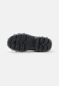 Suela de zapato de goma negra con un patrón de banda de rodadura en zigzag, con nodos de tracción elevados y un área central suave para mayor agarre.