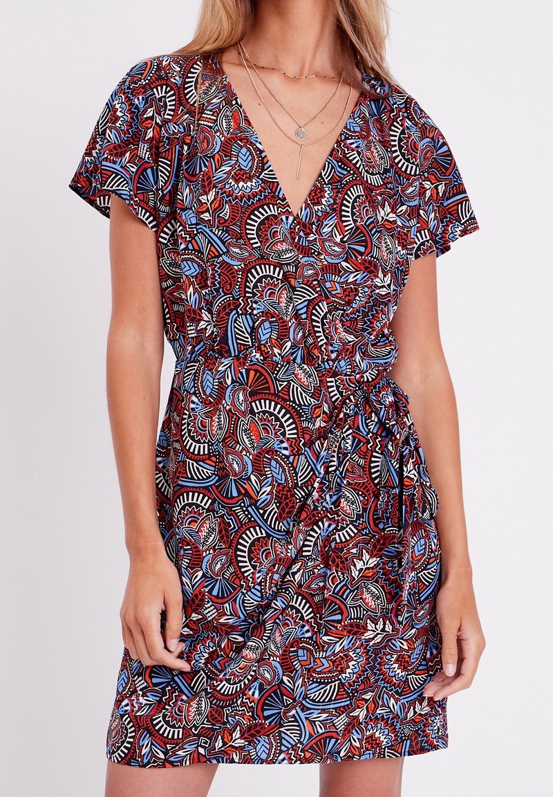 Robe portefeuille à fleurs rouges et bleues avec manches courtes, encolure en V et détail de taille froncée. Présente un tissu à motif et une longueur jusqu'aux genoux.