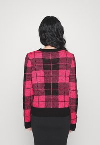 Rosa-schwarz karierter Pullover mit rundem Ausschnitt sowie gerippten Bündchen an Ärmeln und Saum, aus einem strukturierten Strickmaterial gefertigt.