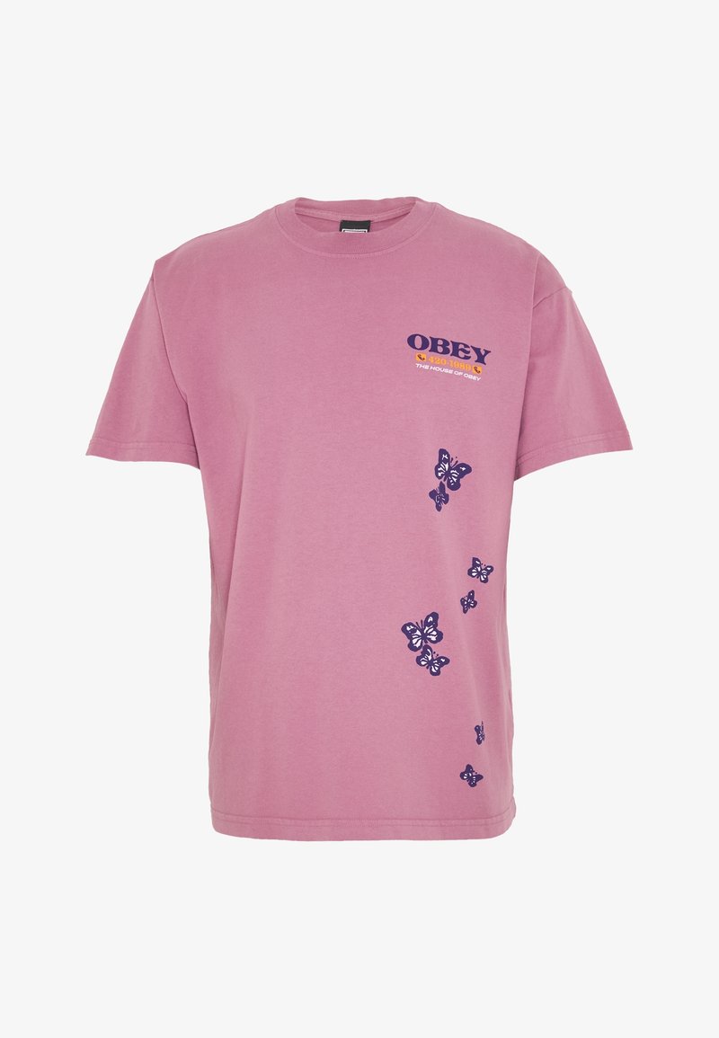 Růžové bavlněné tričko s fialovým nápisem "OBEY" na levé straně hrudi a motivy motýlů podél boku. Klasický střih s kulatým výstřihem.