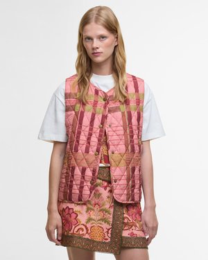 Gequiltede vest in roze, groen en bruine patronen. Voorzien van gouden knopen en een middellange pasvorm, gecombineerd met een bloemenprint rok.