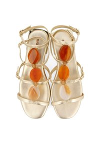 Sandalias doradas con múltiples correas que presentan piedras decorativas redondas en tonos naranja y crema. Textura metálica suave y diseño de punta abierta.