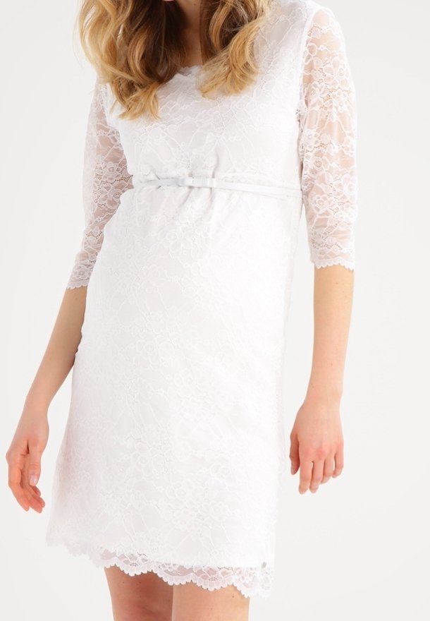 Robe en dentelle blanche avec des manches trois-quarts, un buste ajusté et une ceinture en satin à la taille. Ourlet festonné et détails en dentelle florale.