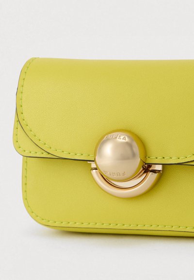 Portefeuille en cuir vert citron avec un fermoir rond en or, présentant des accents de couture et une texture lisse. Design compact avec fermeture à rabat.