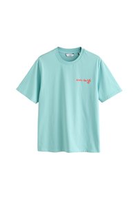 T-shirt bleu clair à manches courtes avec col rond, petit texte rouge en cursive sur le côté gauche de la poitrine et étiquette de marque blanche à l’intérieur du col.