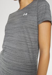 Grå atletisk t-shirt med meleret tekstur, korte ærmer og en lille hvid logo øverst til venstre. Klassisk rund halsudskæring.