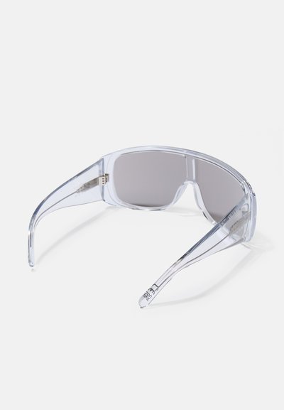 Óculos de sol transparentes com lentes cinzas, apresentando uma forma retangular, design elegante e templos ligeiramente curvados. Sem marcas visíveis.