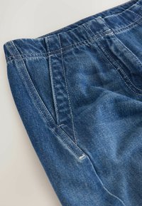 Dunkelblaue Jeans aus Denim mit leicht verwaschenem Finish, ausgestattet mit einem dehnbaren Bund, Seitentaschen und sichtbaren Nahtdetails.