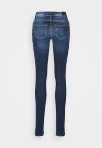 Jeans skinny azul escuro com uma textura de denim suave, design padrão de cinco bolsos, detalhes cosidos e um ligeiro desbotamento nas coxas.