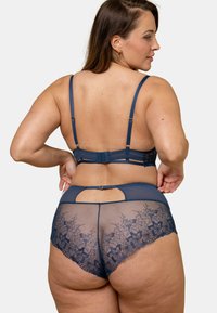 Ensemble soutien-gorge et culotte en dentelle marine comprenant un mesh transparent avec broderie florale, des bretelles réglables et un détail en forme de trou de serrure sur la taille.