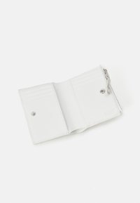 Portefeuille en cuir blanc avec plusieurs emplacements pour cartes, fermeture à pression et compartiment zippé. Présente un logo en relief et une texture lisse.
