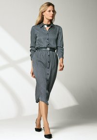 Schwarz-weiße gemusterte Hemdkleid mit kragen, langen Ärmeln, tailliertem Bund mit passendem Gürtel und knöchellangem Saum.