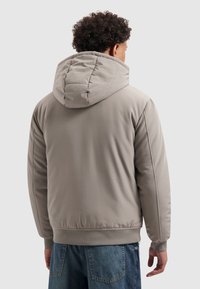 Grijze gewatteerde jas met capuchon, voorzien van geribbelde manchetten en zoom, een gladde textuur en een gestroomlijnde silhouet.