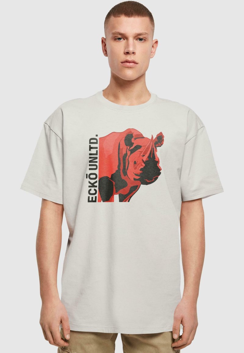 Lichtgrijze t-shirt met een groot rood en zwart neushoornontwerp en "ECKŌ UNLTD." tekst aan de linkerkant. Korte mouwen en een ontspannen pasvorm.