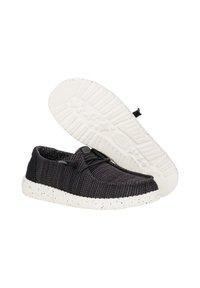 Scarpe casual in maglia nera con suola maculata bianca, dotate di un sistema di lacci flessibile e tomaia testurizzata per la traspirabilità.
