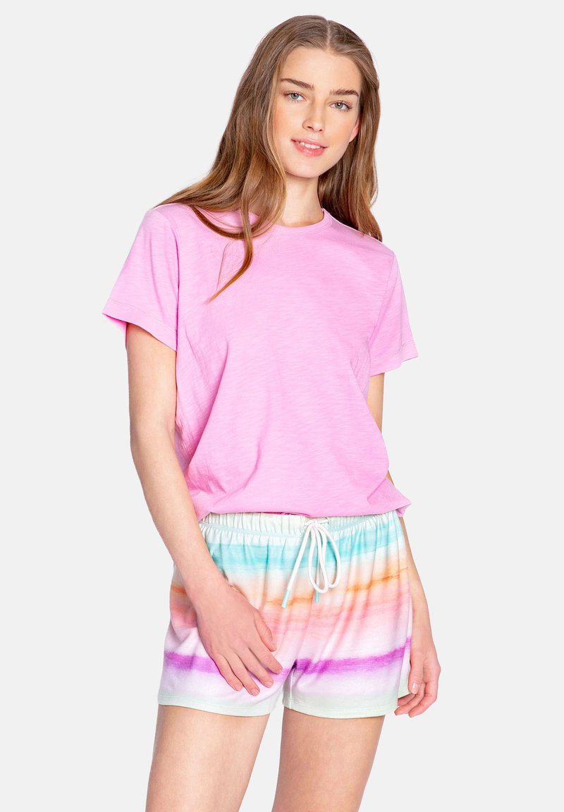 Camiseta rosa de manga corta combinada con pantalones cortos de tie-dye multicolores con rayas horizontales en tonos pastel y una cinturilla elástica con cordón.