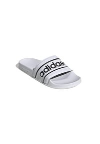 Vit slide sandal med en texturerad yta, med två svarta ränder och "adidas"-loggan på remmen. Platt sula designad för avslappnad användning.