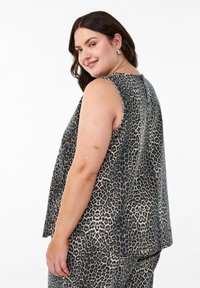 Mouwloze top in dierenprint met een ontspannen pasvorm, gemaakt van zachte stof. Kleuren zijn zwart en beige, met een ronde halslijn.