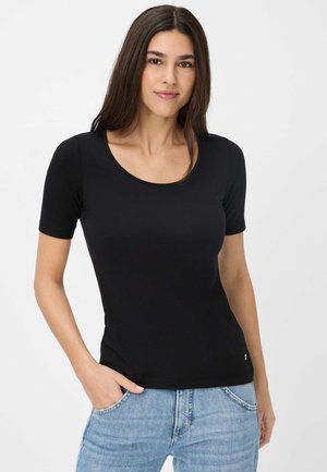 Schwarzes T-Shirt mit kurzen Ärmeln und Rundhalsausschnitt, weicher Textur und tailliertem Design. Getragen mit hellblauen Jeans, die eine Tasche haben.