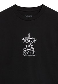 Camiseta de algodón negra con un gráfico blanco de un conejo de dibujos animados sosteniendo un control remoto, con el logo de "VANS" debajo. Diseño clásico de cuello redondo.