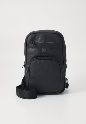 Borsa a spalla in pelle nera con finitura testurizzata, dotata di una tasca frontale con zip, dettaglio del logo e tracolla regolabile. Design compatto.