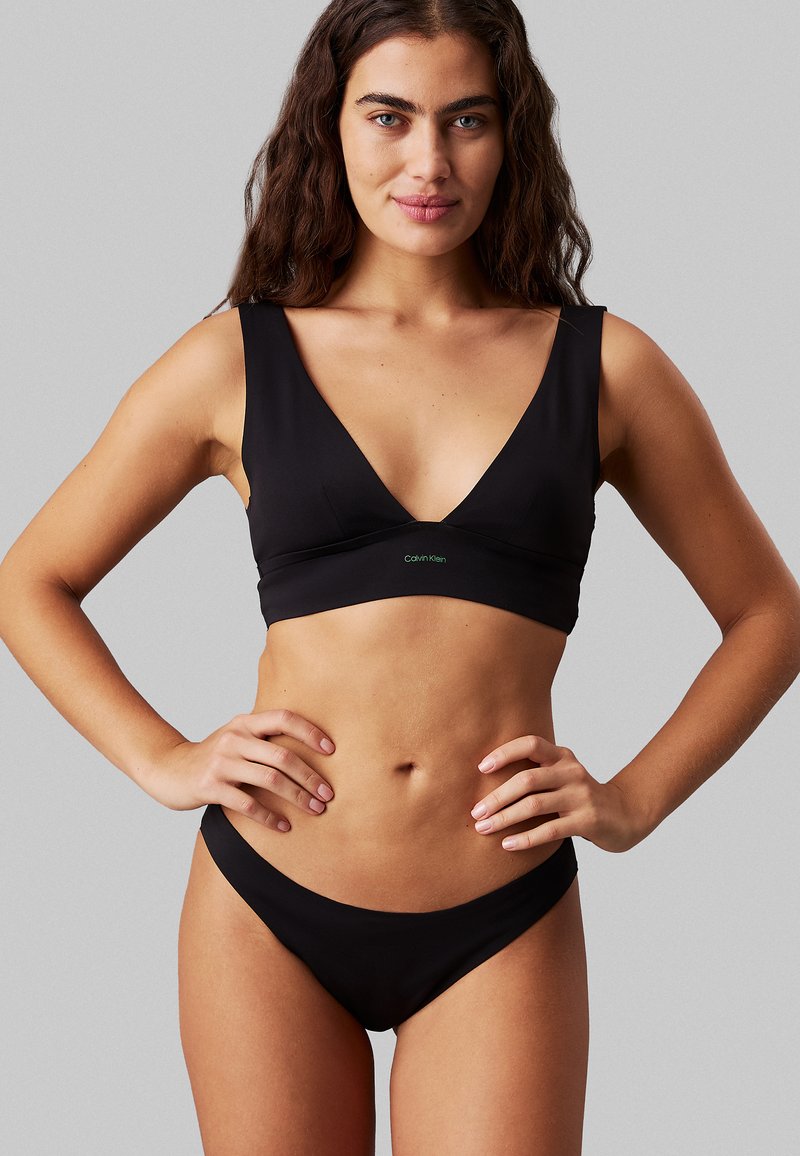Conjunto de bikini negro que incluye un bralette triangular y parte inferior de cintura baja. Está hecho de una tela suave con un diseño minimalista y un pequeño detalle de logo.