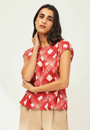 Red patterned blouse with short sleeves, featuring a checkered design in varying shades of red and white, slightly flared bottom hem.