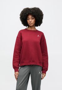 Μακρυμάνικη μπλούζα μπορντό από μαλακό ύφασμα, με στρογγυλή λαιμόκοψη. Λευκή κεντημένη λογότυπο στο στήθος. Γκρι αθλητικό παντελόνι με διακριτικές λεπτομέρειες.