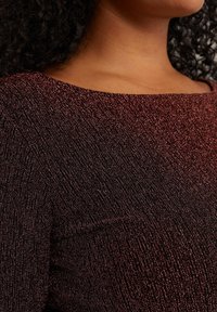 Top borgogna con texture e una leggera lucentezza, caratterizzato da un ampio scollo e una silhouette aderente. Il tessuto ha una finitura elastica e scintillante.